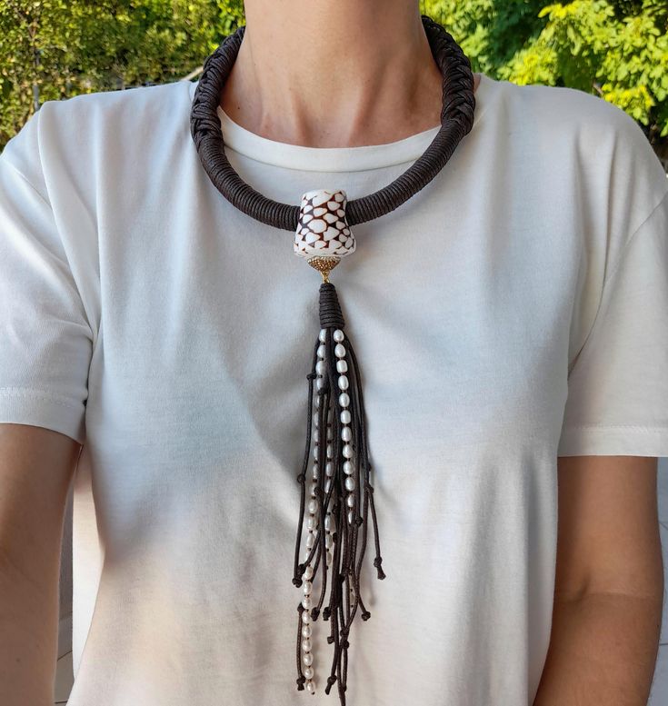 a woman wearing a black and white necklace with tassels on it's neck