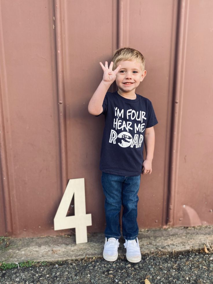 a young boy standing in front of a number four sign and making the peace sign