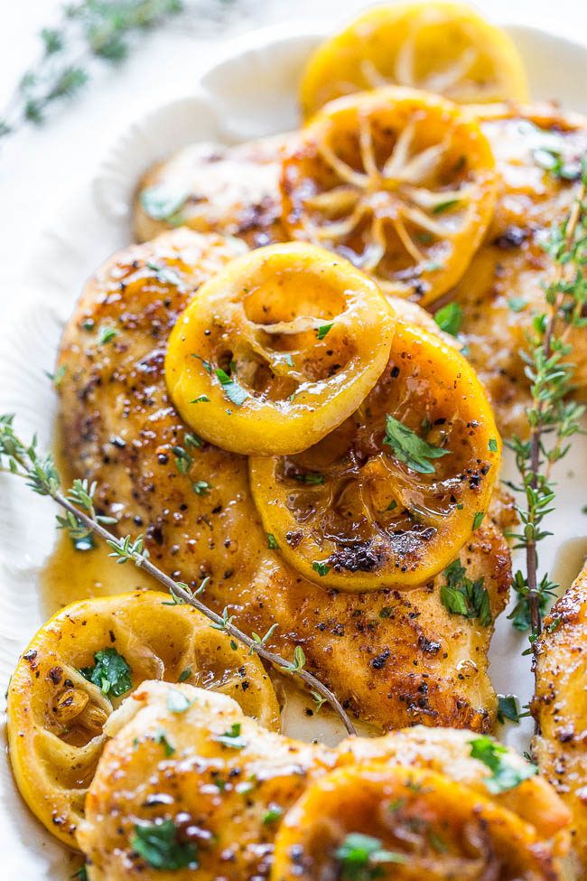 grilled chicken with lemons and herbs on a white plate