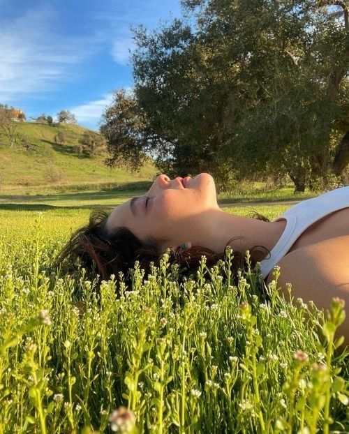 a woman laying in the grass with her eyes closed