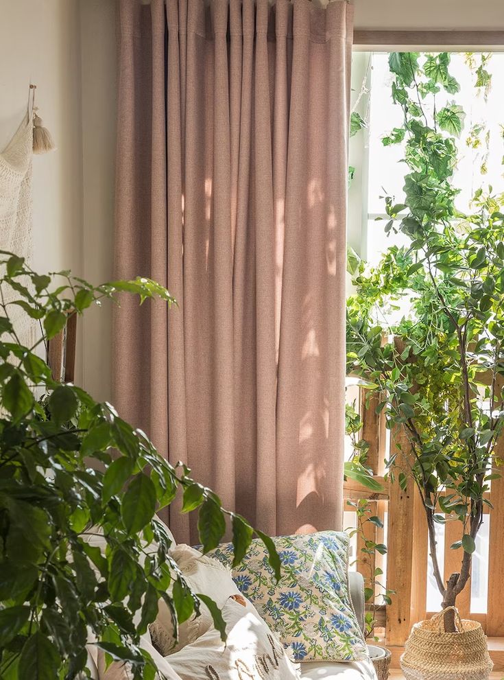 a living room filled with lots of furniture and plants in front of a large window