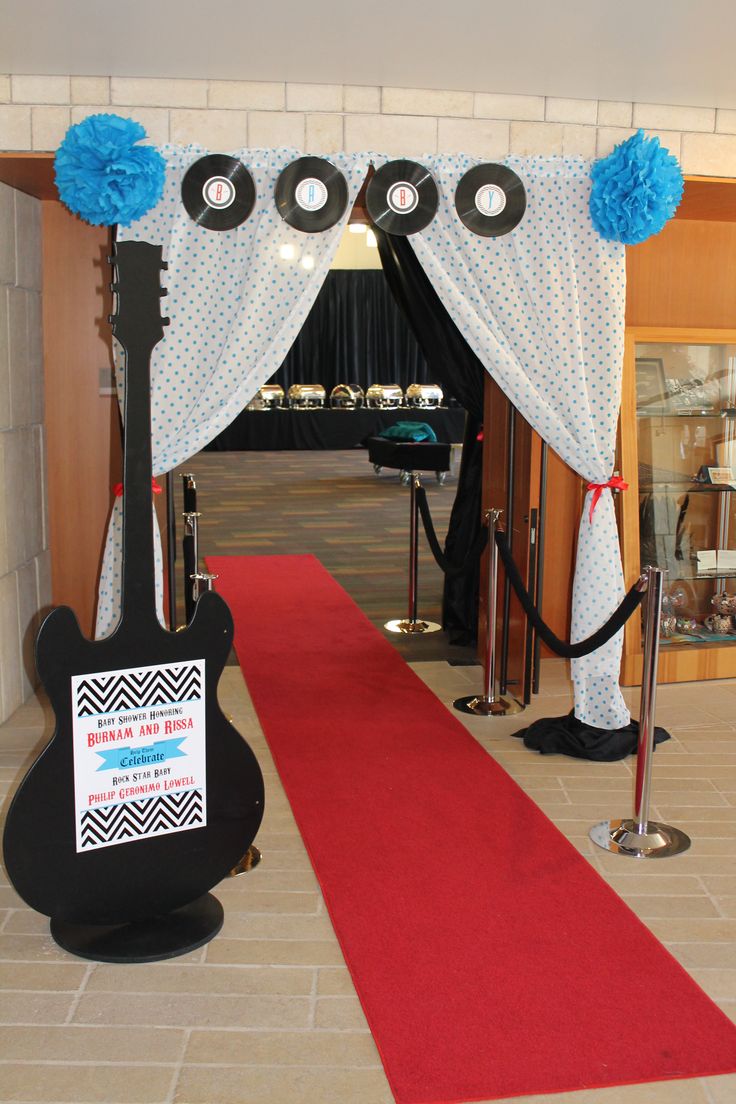 a red carpeted area with a guitar on the floor and blue pom poms