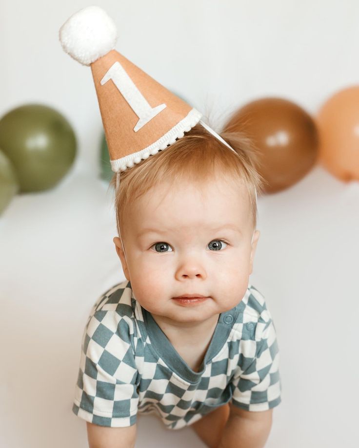 a baby is wearing a party hat with the letter l on it's head