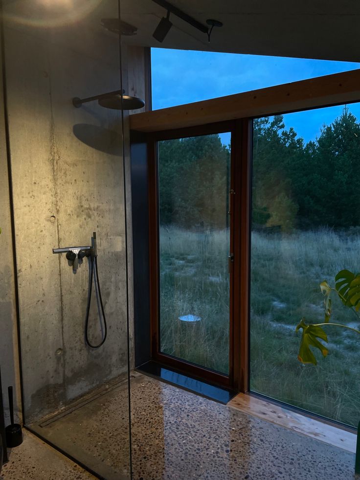 a bathroom with a walk in shower next to a large glass door that leads outside