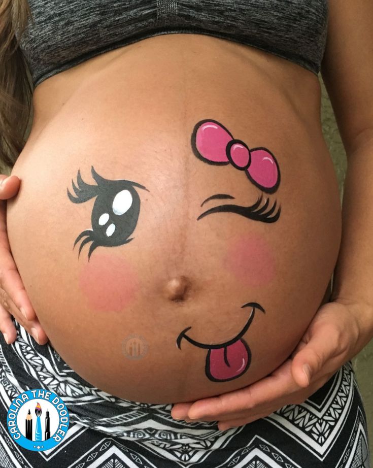 a pregnant woman holding her belly with the face of a cartoon character painted on it