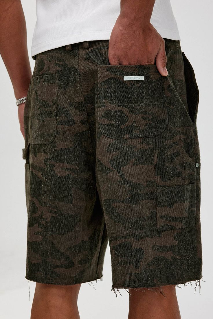 The Frayed Double-Knee Camo Cargo Shorts masterfully blend military elements with street style. These slightly oversized shorts feature an all-over camouflage print and a durable double-knee design for added toughness. The frayed hem adds an edgy touch, while the back pocket is adorned with a metal logo badge for a distinctive look. Crafted from premium 100% cotton fabric (370g/m²), these shorts ensure both comfort and durability, making them perfect for any urban adventure. All-over camouflage Streetwear Short Cargo Jeans With Multiple Pockets, Short Cargo Jeans With Multiple Pockets For Streetwear, Camouflage Cargo Jeans With Patch Pockets For Streetwear, Military Style Bottoms With Hip Pockets For Streetwear, Military Style Cargo Jeans With Patch Pockets For Streetwear, Military Style Cargo Shorts With Side Pockets, Military Cargo Shorts With Side Pockets, Military Style Cargo Bottoms For Streetwear, Military Bottoms With Side Pockets For Streetwear