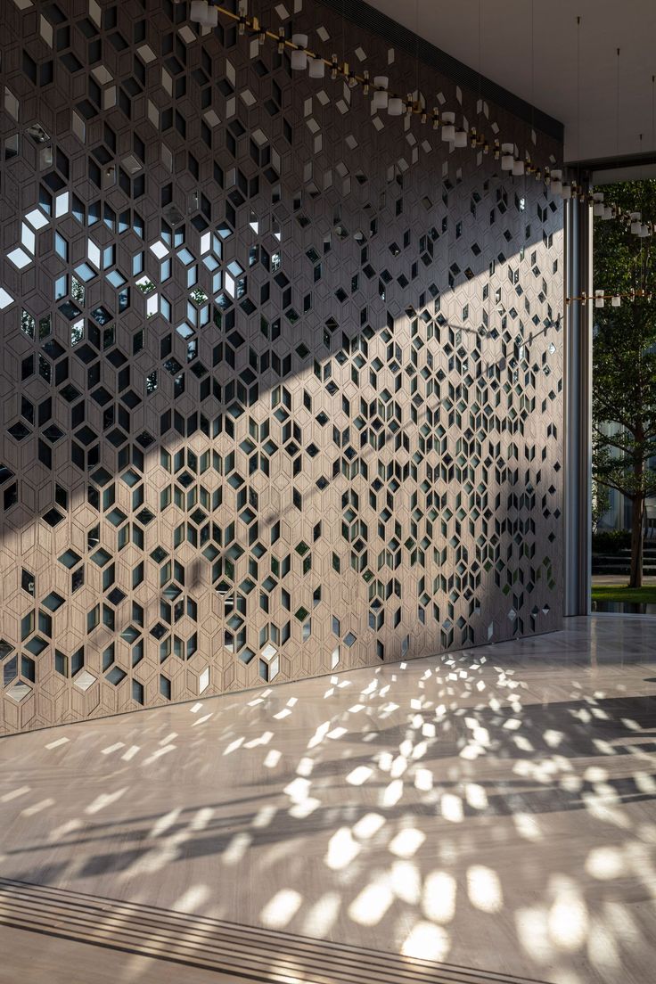 an intricately designed wall in front of a building with lots of sunlight coming through the windows