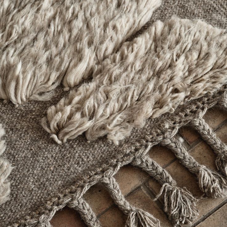 an area rug with fringes on top of it and a brick floor in the background