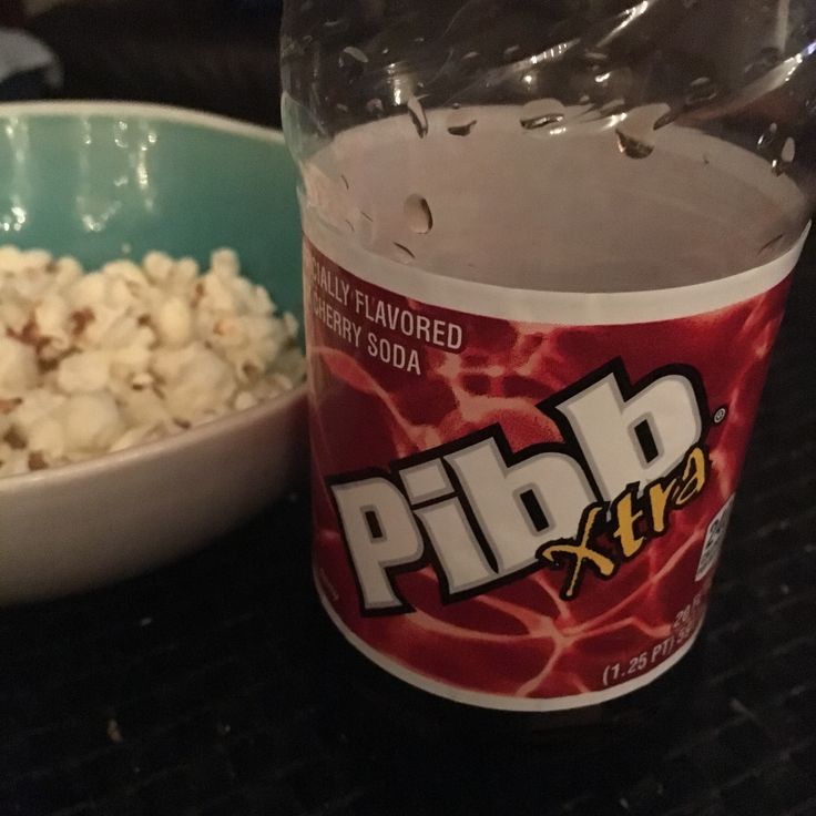 a bowl of popcorn next to a bottle of soda