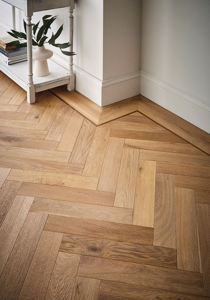 an empty room with wood flooring and a plant on the table in front of it