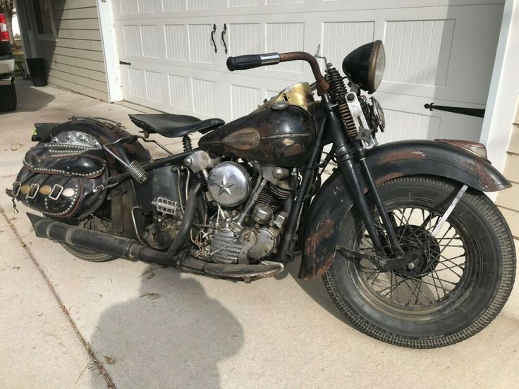 an old motorcycle is parked in front of a garage with a white door behind it