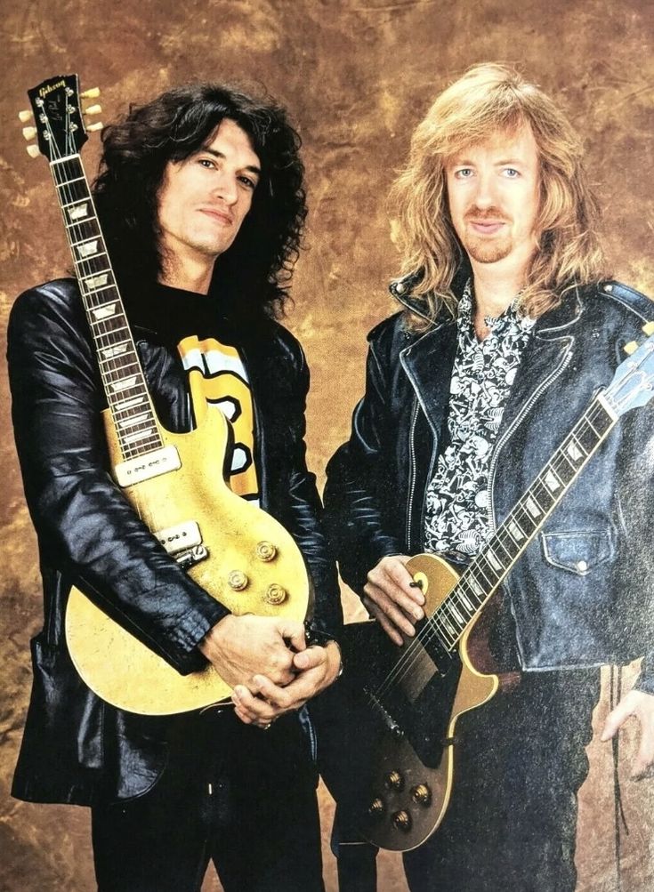 two men standing next to each other holding guitars