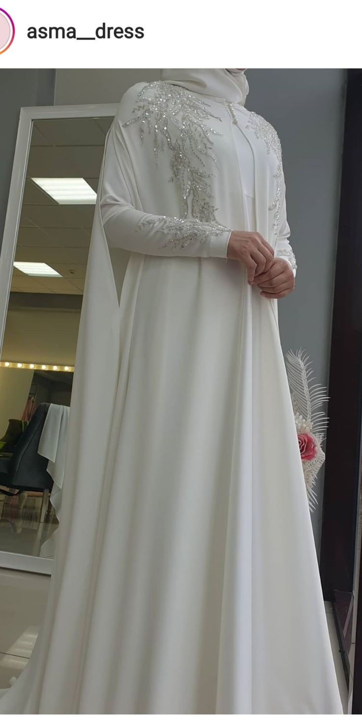 a woman in a white dress standing next to a mirror with her hands on her hips