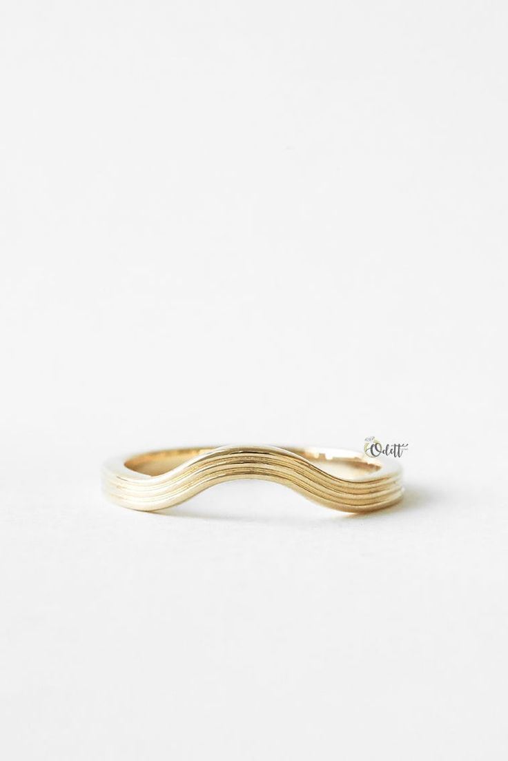 a gold ring with three wavy lines on it's side, against a white background