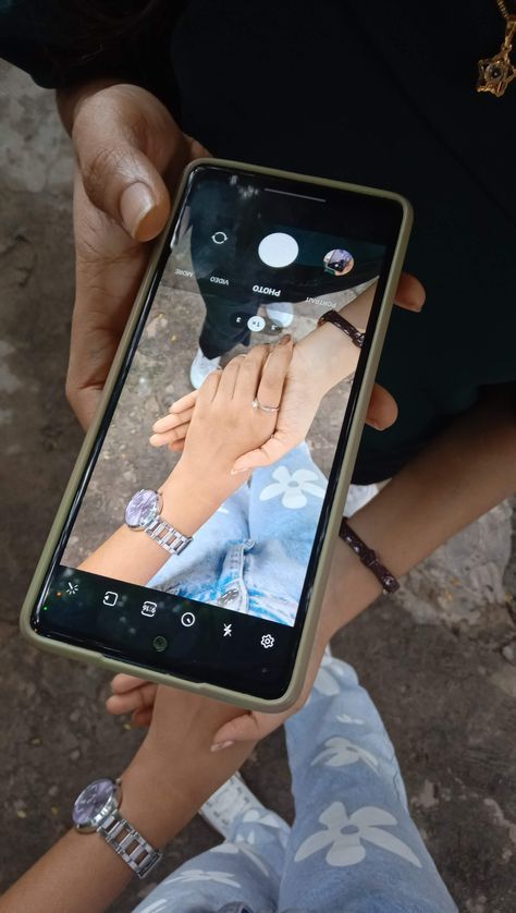 a person holding up a cell phone with pictures on the screen and hands touching each other