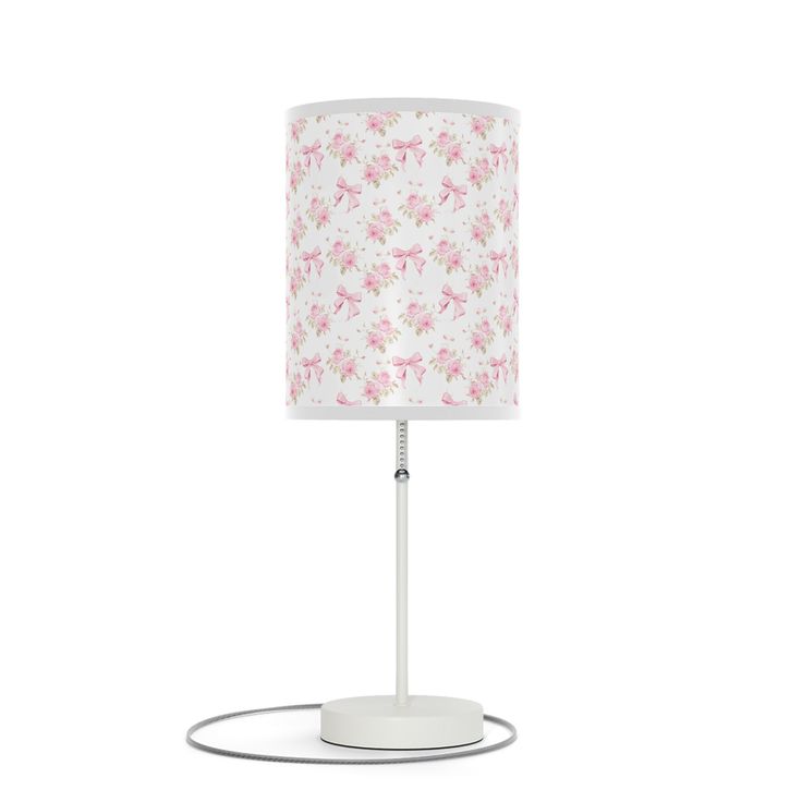 a white table lamp with pink flowers on the lampshade and an electric plugged in