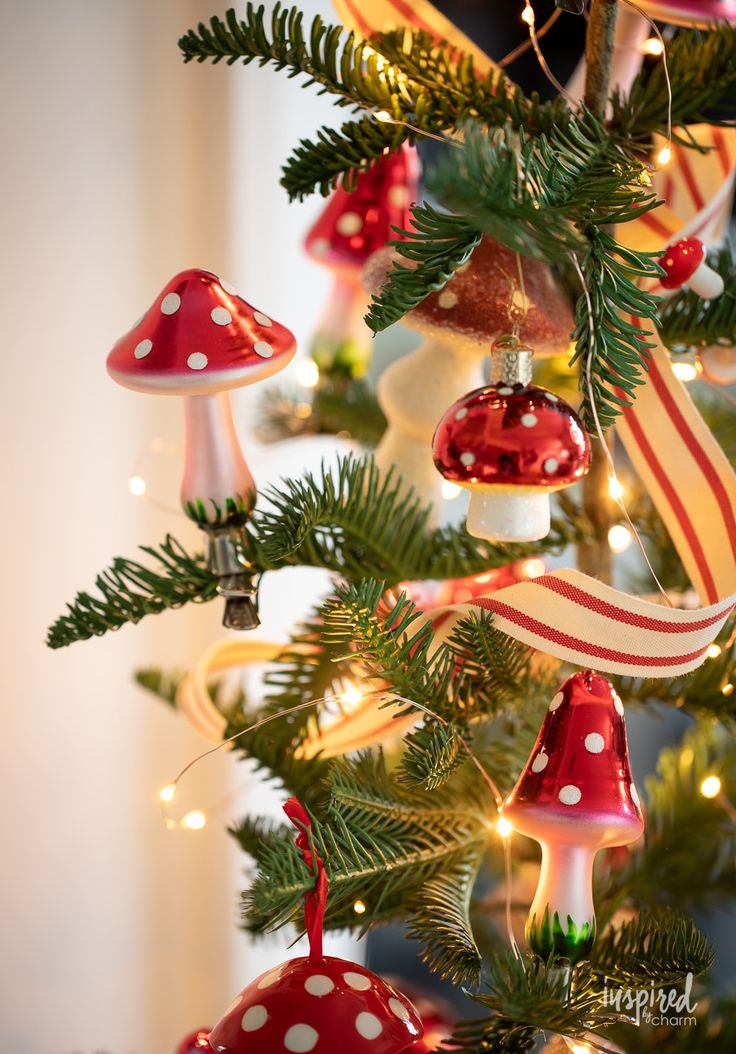 a christmas tree with red and white ornaments on it's branches, including mushrooms