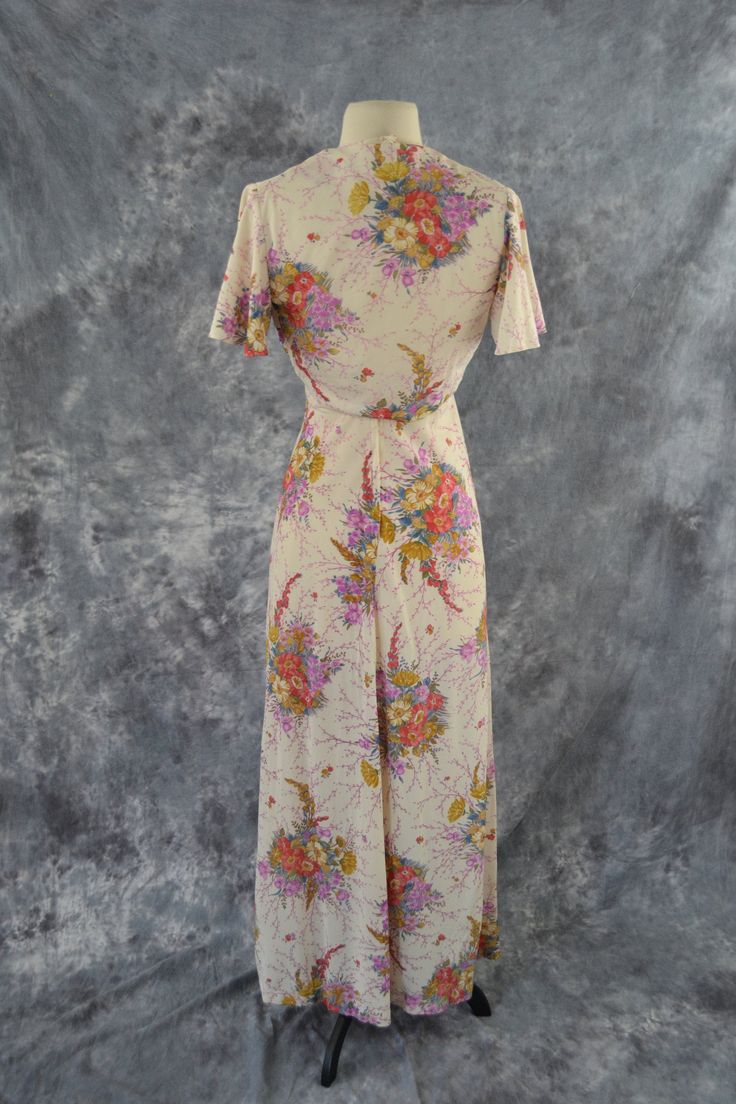 1970's Ivory and Pastel Colored Floral Print Maxi Dress and Matching Bolero A-line dress features spaghetti straps with an empire waist. Print is of bouquets of pastel colors in purple, red, blue, and yellow flowers. A zipper up the back and the halter top has buttons on the back. The matching bolero has a cap sleeve, the bolero ties under the bust. Label: Unknown - No Tag Present Measurements are taken flat; Dress Neck: 12 inches Bust: 13 inches Waist: 14 inches Hips: 18 1/2 inches Length (Top Vintage V-neck Dress For Garden Party, Beige Vintage V-neck Dress, Vintage Full Length Daywear Dress, Vintage Full Length Dress For Spring, Vintage Flowy Dresses For Daywear, Vintage Beige V-neck Maxi Dress, Flowy Vintage Dresses For Daywear, Vintage Spring Maxi Dress With Vintage Print, Spring Vintage Maxi Dress With Vintage Print