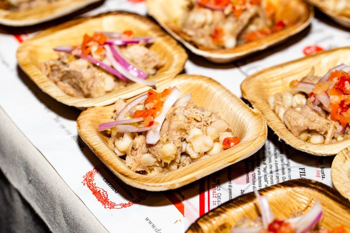 small wooden plates filled with food on top of a white table cloth covered in red and yellow napkins