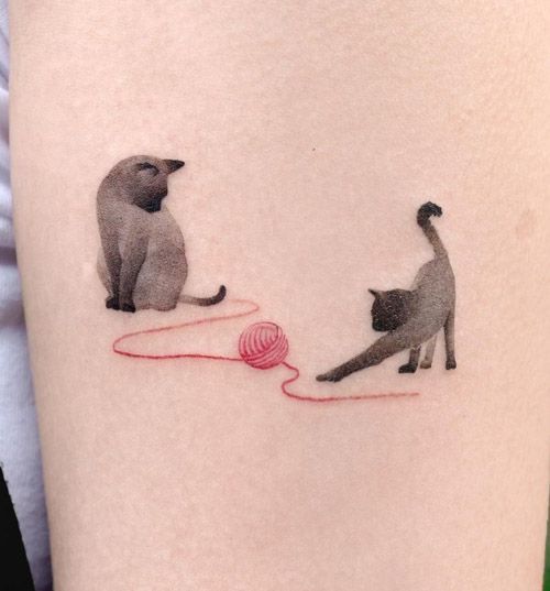 two cats playing with a ball of yarn tattoo on the left thigh and right leg