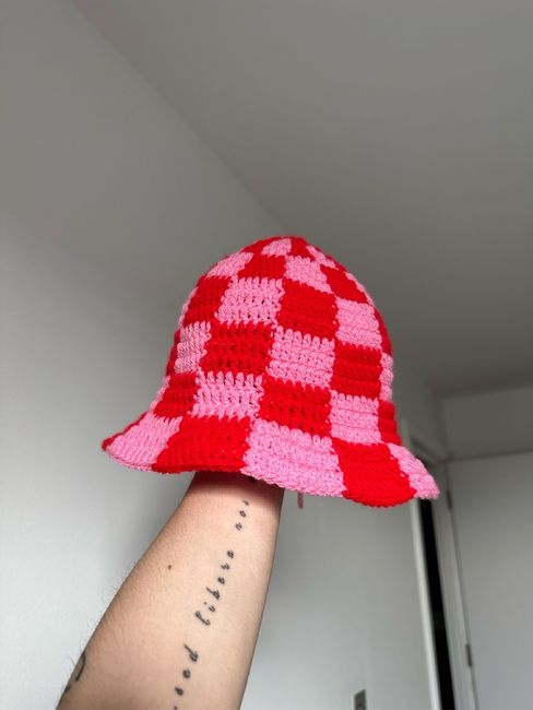 a person's arm with a pink and red hat on top of their head