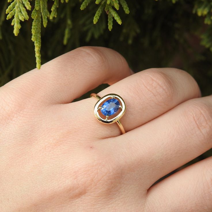 a woman's hand with a ring on it and a tree in the background