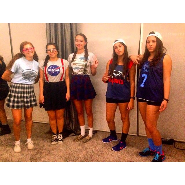 four girls standing next to each other in front of a mirror wearing skirts and t - shirts