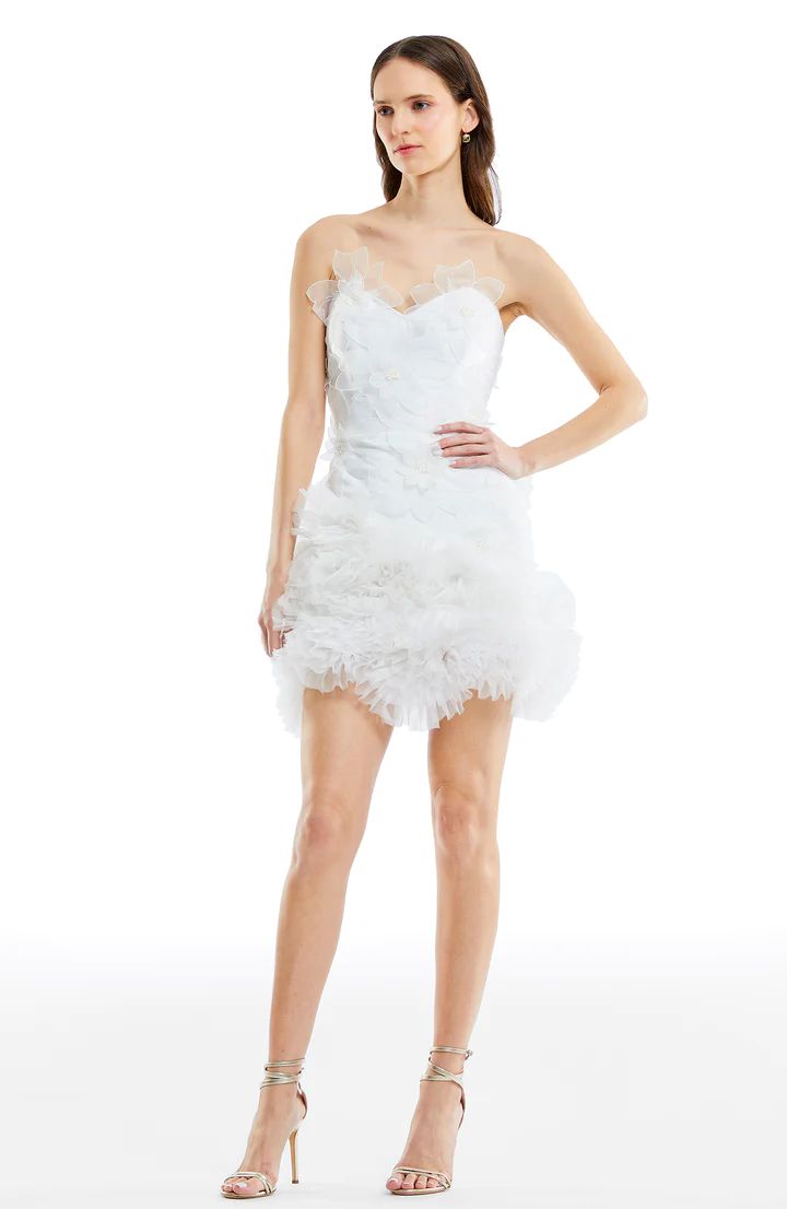 a woman in a short white dress with feathers on the bottom and one leg up