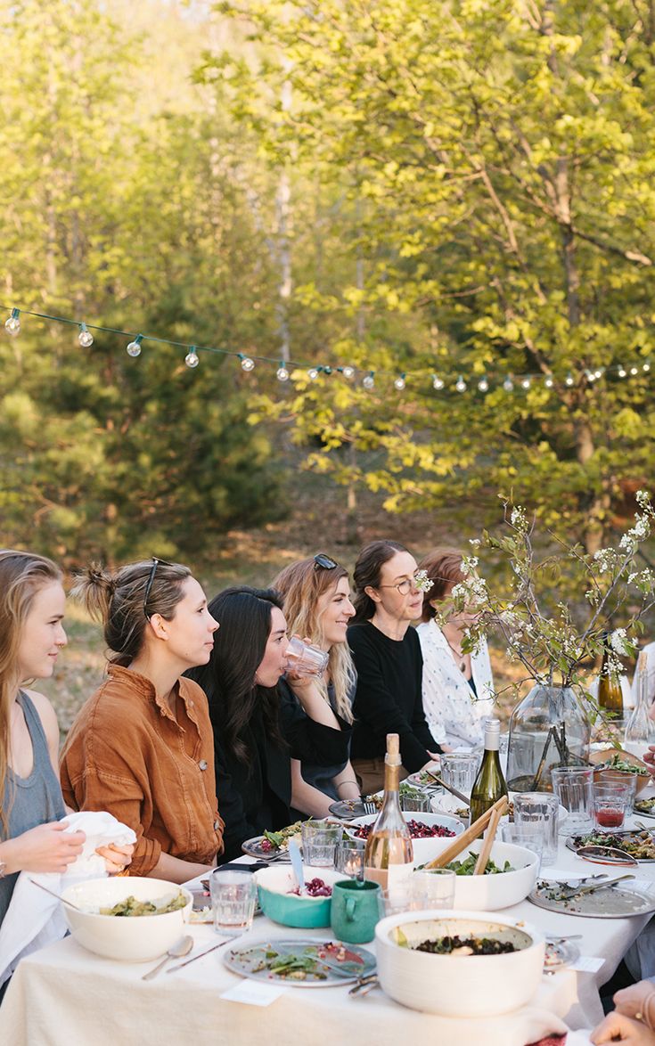 a group of people sitting around a table with food and drinks