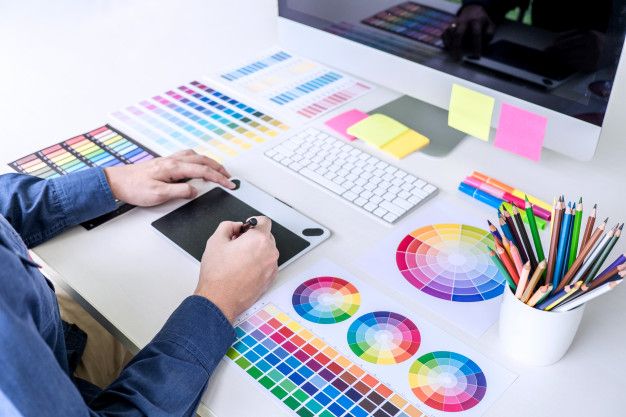 a man sitting at a desk working on his computer with color swatches and markers