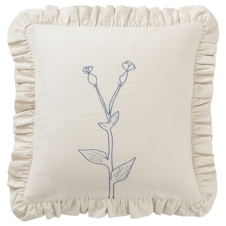 a white pillow with a blue embroidered flower on the front and back of it, along with a ruffled edge