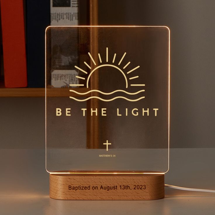 a lighted glass plaque with the words, be the light on it