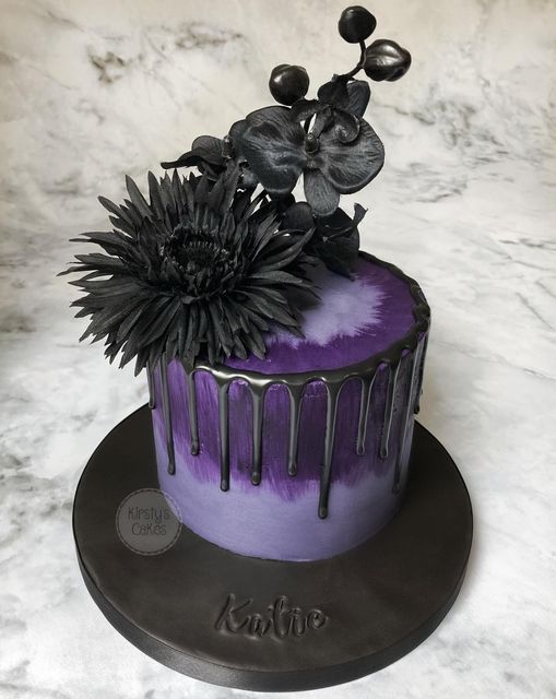 a purple and black cake with flowers on top