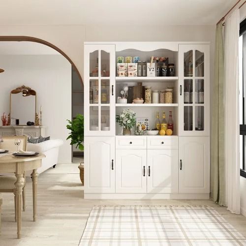 a dining room table and chairs with white cabinets in front of the wall, along with an arched doorway leading to another room