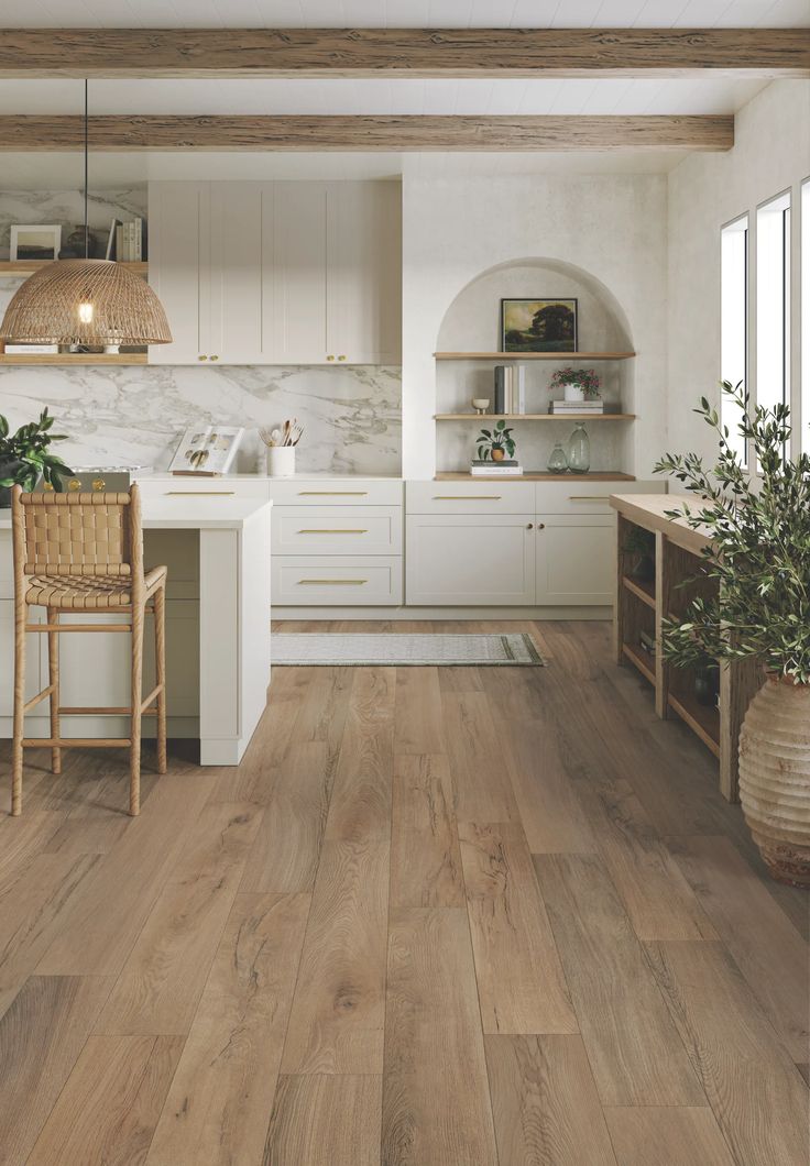 a kitchen with wood flooring and white cabinetry is pictured in this image, there are two chairs at the counter