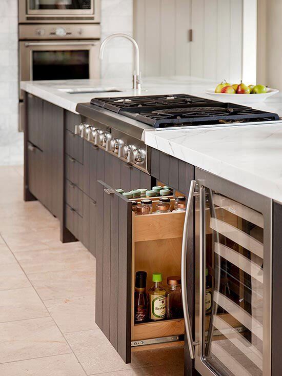 an open cabinet in the middle of a kitchen with stainless steel appliances and marble counter tops