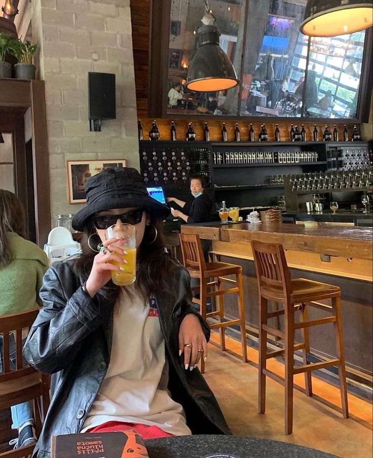 a woman sitting at a table with a drink in her hand