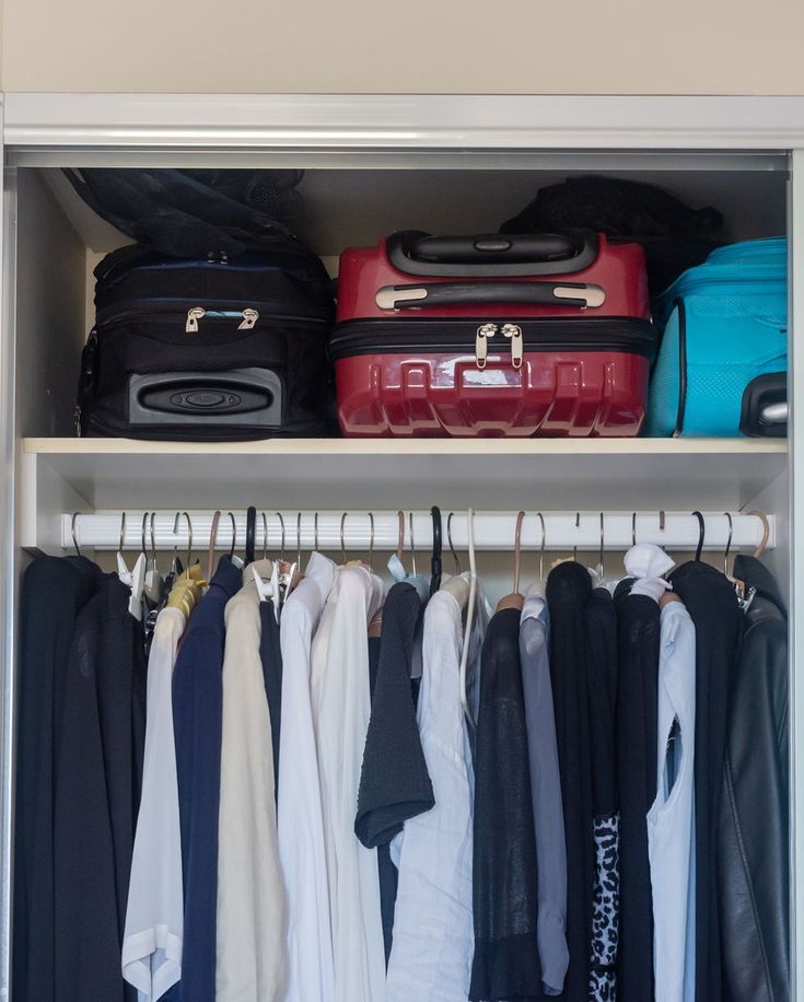 an organized closet with luggage and clothes