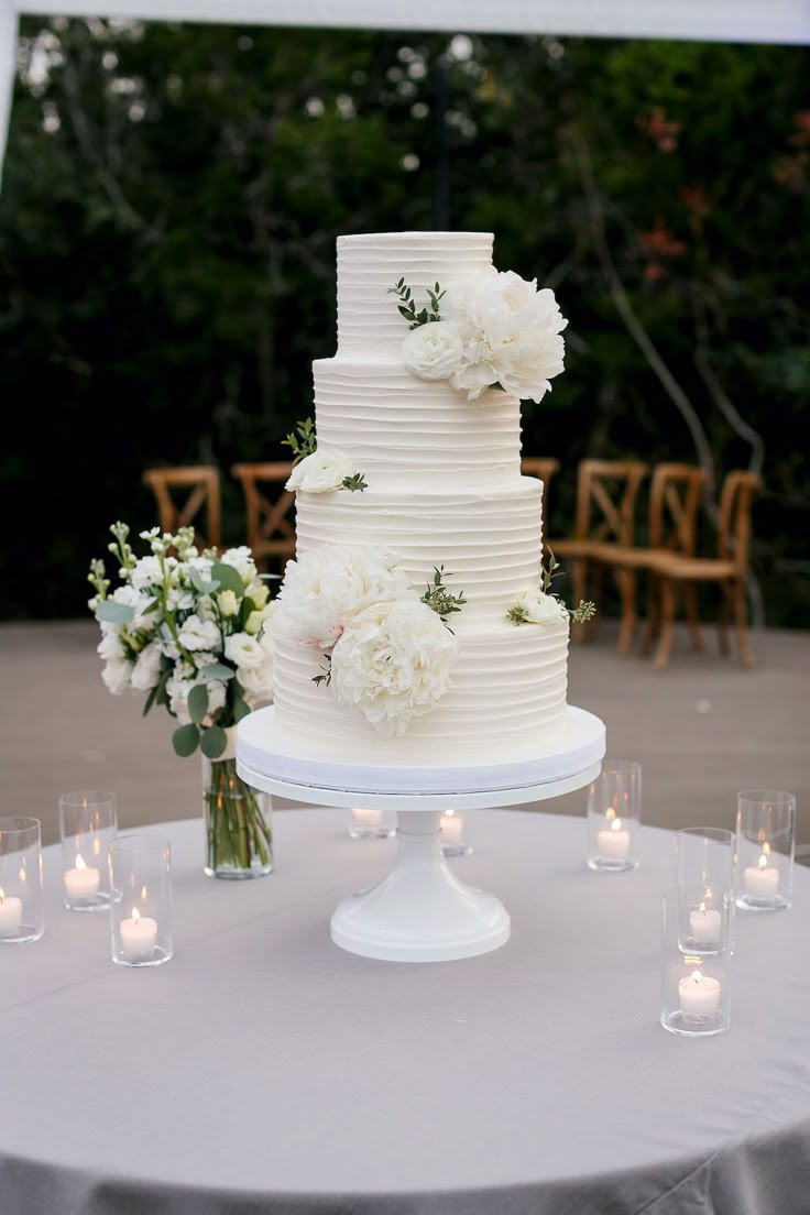 a wedding cake sitting on top of a table next to some flowers and lit candles