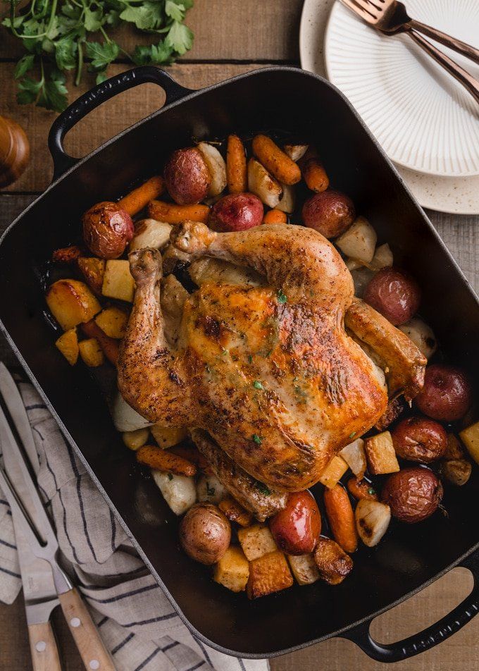 a roasting pan filled with chicken, potatoes and carrots