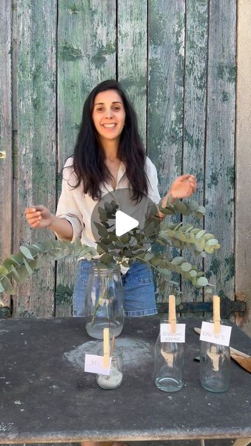 a woman standing in front of a table with vases and candles