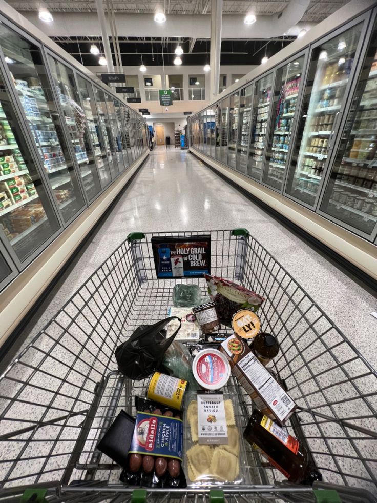 a shopping cart filled with lots of food in a grocery store's empty aisle