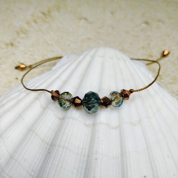 This is a beautiful bracelet with faceted crystal smokey blue beads and antique gold bicone beads.  It is made with high quality nylon cord in an antique gold color. It opens up to 9" to slip over the largest part of your hand and then you pull the ends together to fit around your wrist. ✶ QUICK SHIPPING! ✶ I make every effort to get your order processed and shipped as soon as possible. Order processing takes 1-2 days, and I typically ship the orders the same day they are processed. Orders placed on the weekend (Sat/Sun) may take an additional 1-2 days to process and ship. ✶ RETURNS: While I don't accept returns, your 100% satisfaction is my priority. Please message me with any issues concerning your order and I will do what I can to make it right. Adjustable Faceted Crystal Bohemian Bracelet, Bohemian Adjustable Faceted Crystal Bracelet, Adjustable Faceted Bohemian Crystal Bracelet, Adjustable Beaded Blue Wrap Bracelet, Blue Beaded Hand-strung Bracelets For The Beach, Adjustable Blue Beaded Bracelets Ocean-inspired, Adjustable Blue Glass Stretch Bracelet, Adjustable Hand-strung Blue Pearl Bracelet, String Bracelet Patterns