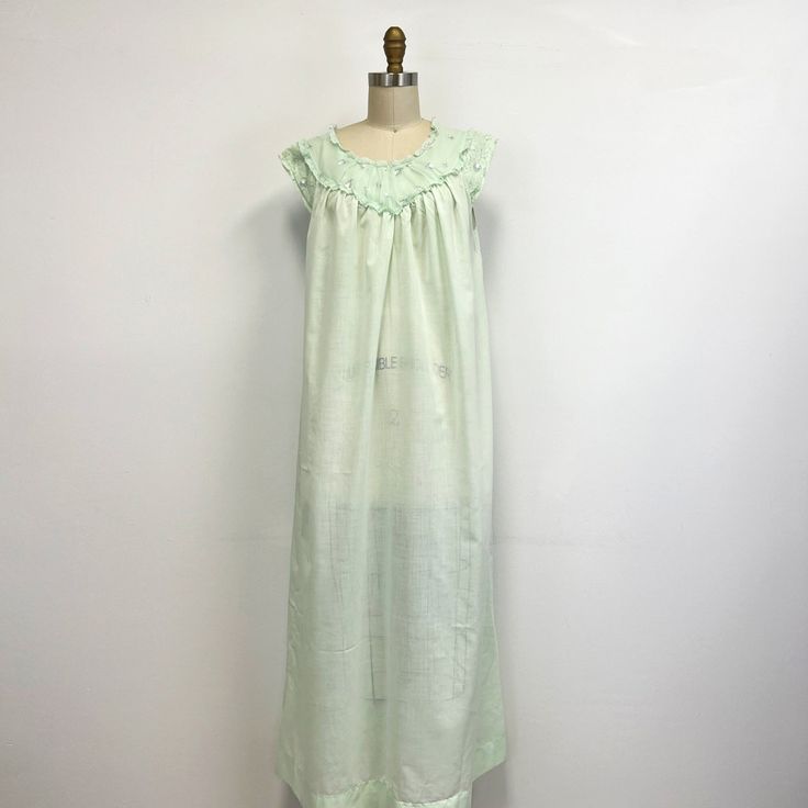 "Vintage 60s nightgown featuring; a rounded neckline trimmed with lace the neckline is covered in gathered, sheer, nylon embroidered with small pink roses this has a small cap style sleeve that is covered in lace gathered across the bust falls straight to the ankle of a light weight, semi sheer cotton and polyester blend in a pale seafoam green, the lace and trim are polyester and nylon labeled \"Perma-Prest Sears\" and tagged a size 32-34 measurements when laid out flat are; 20 inches from pit Lace Trim Dress For Sleepover, Fitted Ruffle Nightgown For Bedtime, Vintage Sleeveless Ruffled Sleepwear, Vintage Ruffled Nightgown For Loungewear, Vintage Nightgown With Ruffles For Loungewear, Sleeveless Lace Nightgown For Home, Vintage Lace Trim Dresses For Loungewear, Vintage Ruffled Nightgown For Sleepovers, Green Lace Trim Nightgown For Loungewear