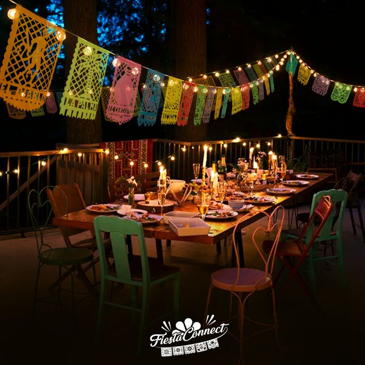 a long table with many chairs and lights on it in front of a balcony at night