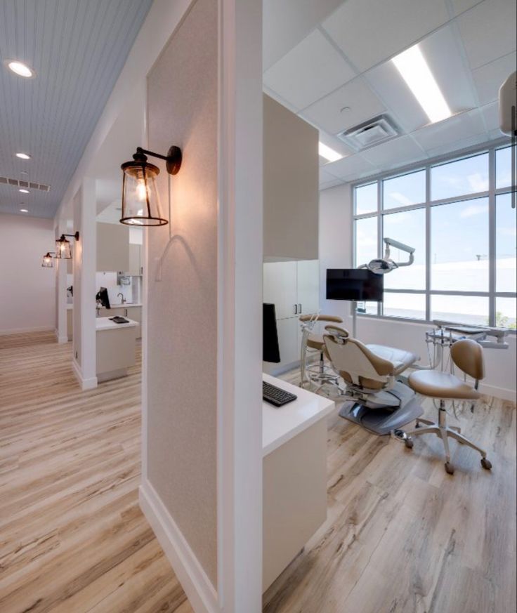 an office with wood flooring and white walls, along with large windows that look out onto the ocean