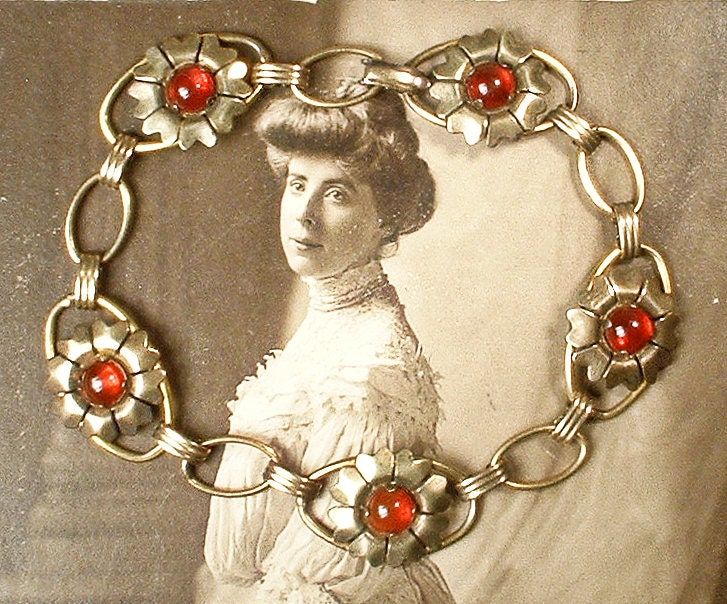 I am SO thrilled to be offering a stunning Art Nouveau/Art Deco circa 1920s -1930s era 12 karat gold over sterling silver dark red glass cabochon flower link bracelet perfect for the Bride  The ornate flower shaped links feature deep red glass cabochon centers.  Note that it was tough to photo as the red is a true red/red with no hints of orange.   Bracelet measures 7 1/8 inches  (17.8 cm) around and is just under 5/8 inches at 9/16 inches (15 mm) wide.  This treasure is in excellent antique condition with no chips or cracks to those luscious glass cabochons the fold over clasp function perfectly.  The treasure has mellowed a tad and I have only lightly cleaned as some, like myself, prefer a bit of patina.  It has that softer authentic antique look and feel that can only be achieved with a Elegant Wedding Bracelets With Vintage Charm, Elegant Antique Gold Wedding Bracelets, Elegant Antique Gold Bracelets For Wedding, Vintage Metal Bracelets For Weddings, Vintage Antique Gold Jewelry For Formal Occasions, Vintage Red Jewelry, Antique Gold Vintage Jewelry For Formal Occasions, Victorian Antique Gold Bracelets For Wedding, Vintage Wedding Bracelet Jewelry