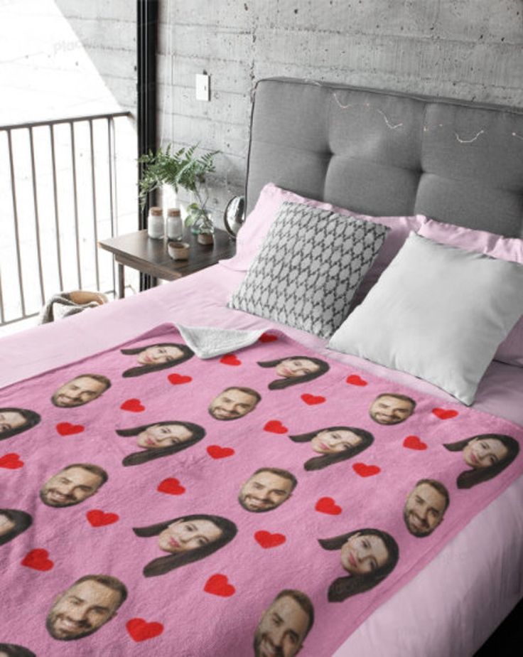 a bed covered in pink sheets and pillows with pictures of people on them