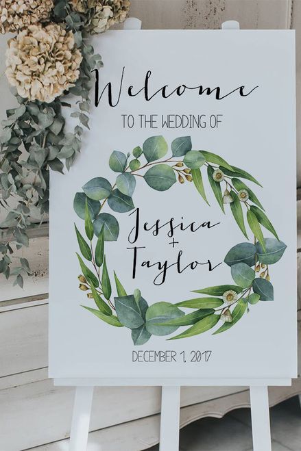 a welcome sign sitting on top of a white easel with greenery around it