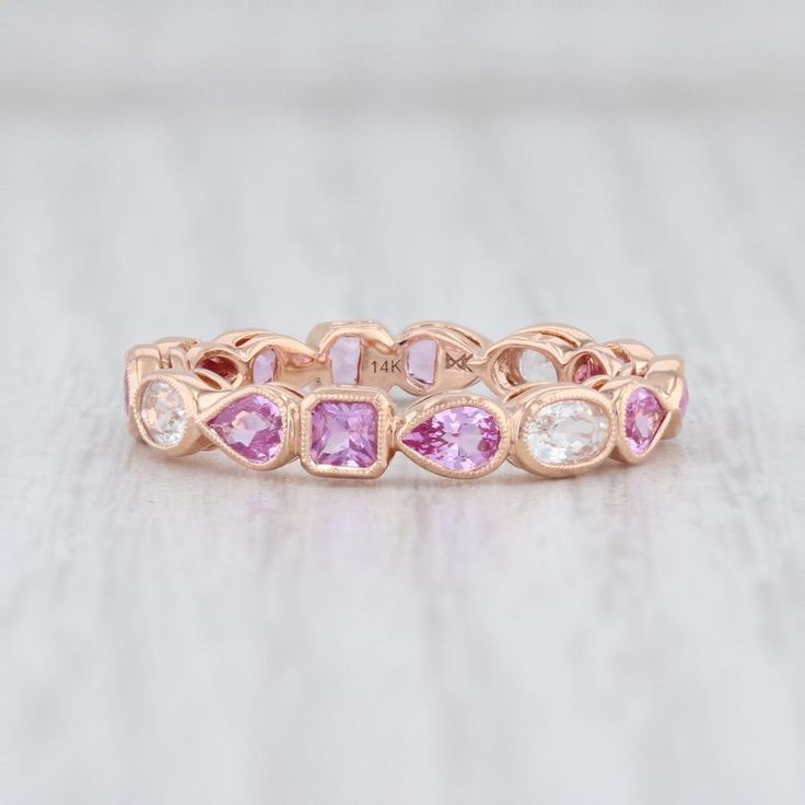 a pink and white diamond ring on top of a table